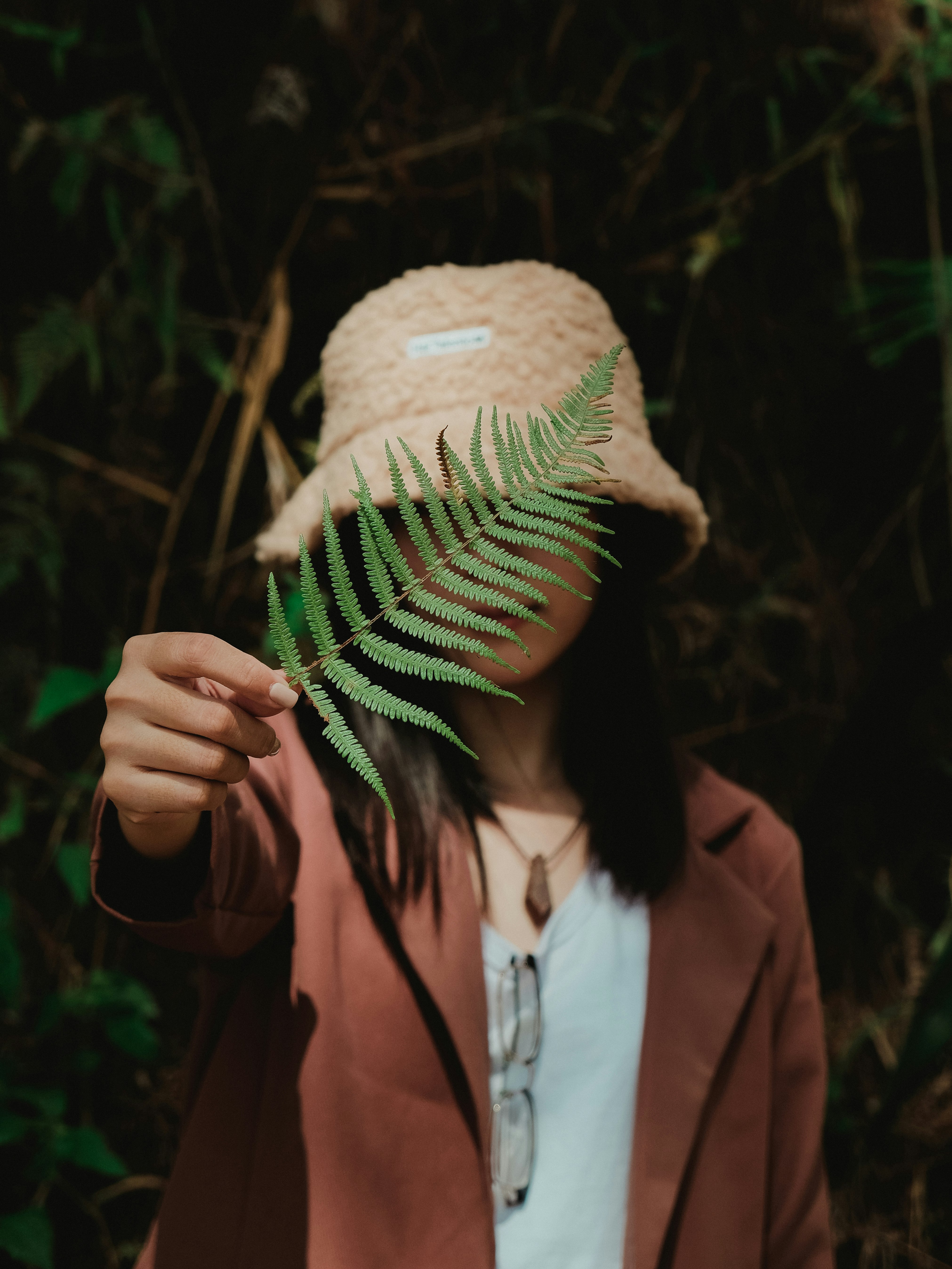 woman in pink jacket holding brown and green leaf